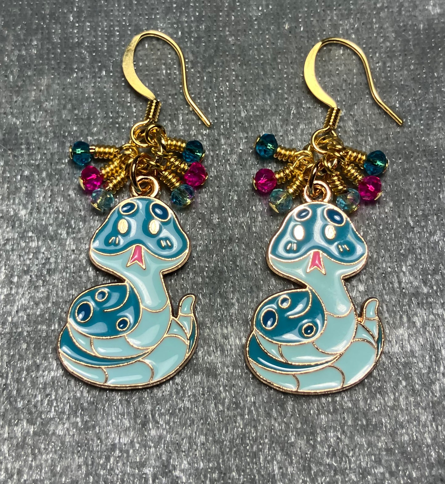 Turquoise and pink enamel snake charm earrings adorned with tiny dangling dark turquoise, hot pink, and light turquoise Chinese crystal beads.