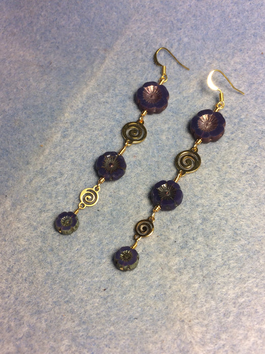 Extra long purple flower bead earrings made with three sizes of purple Czech glass pansy beads joined by gold swirly connectors.