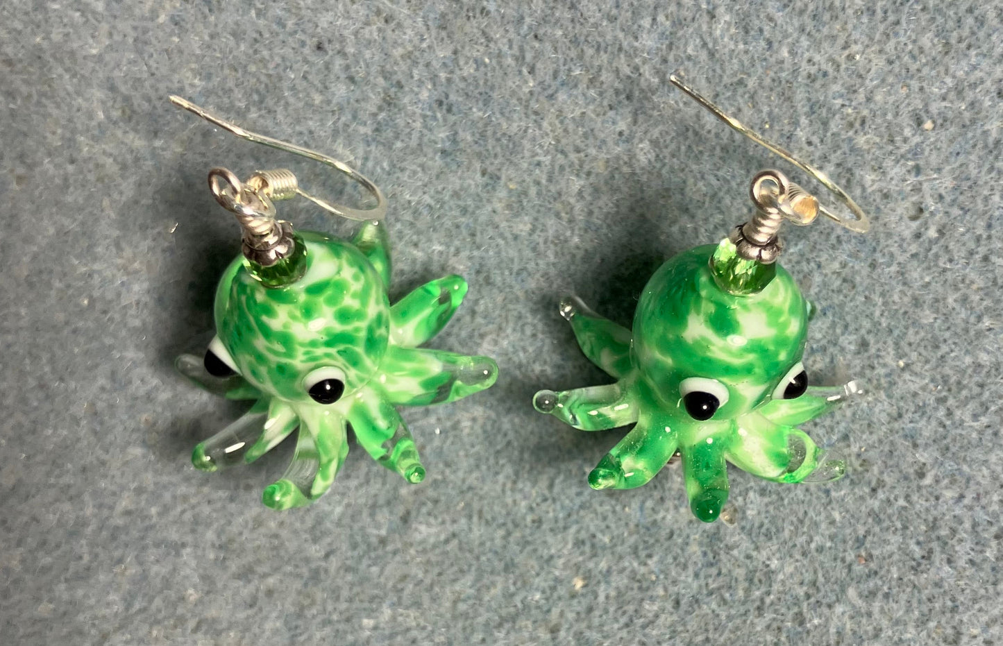 Green and white mottled lamp work octopus bead earrings adorned with green Chinese crystal beads.