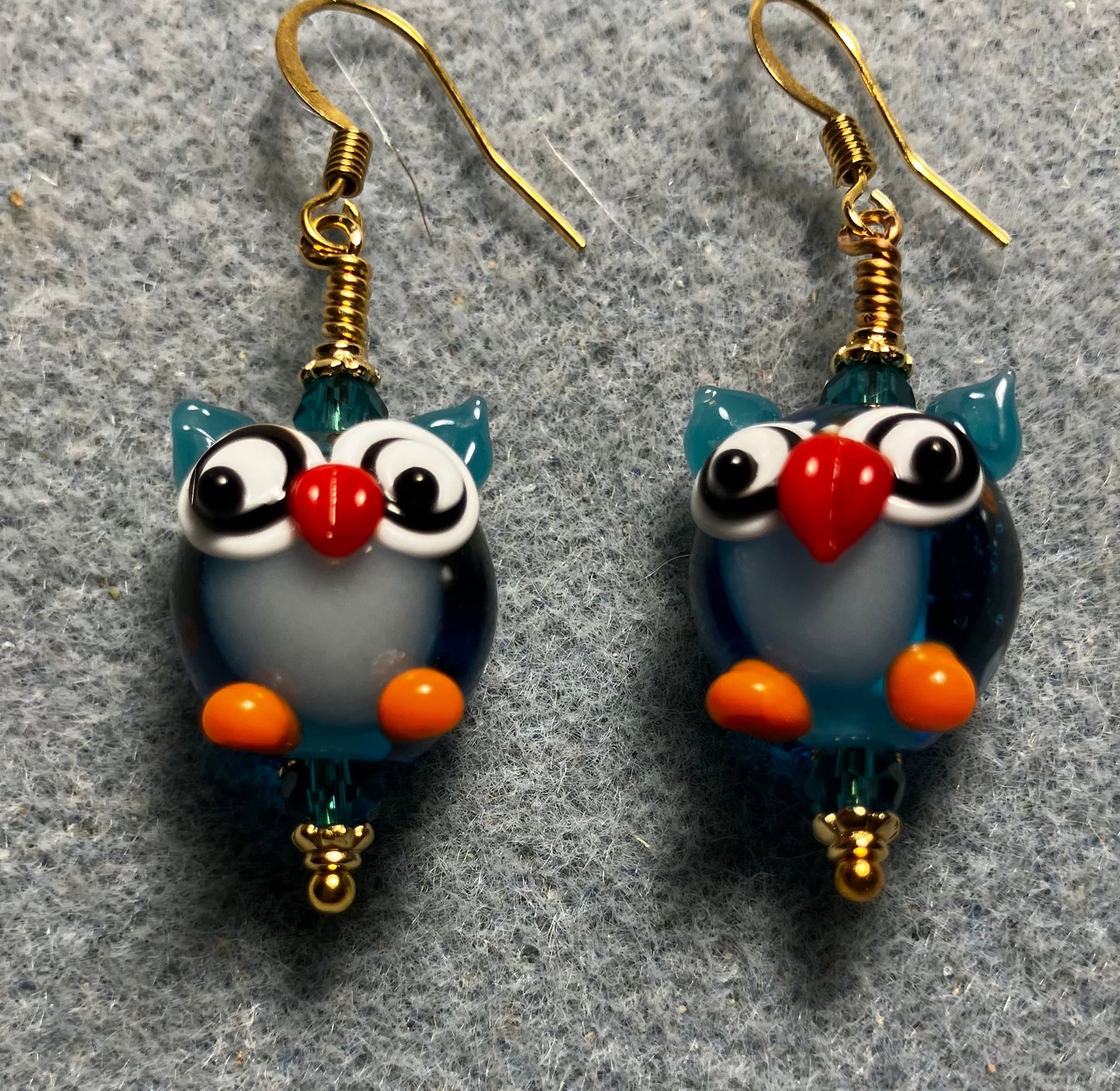 Turquoise, orange, and red lamp work owl bead earrings adorned with turquoise Chinese crystal beads.