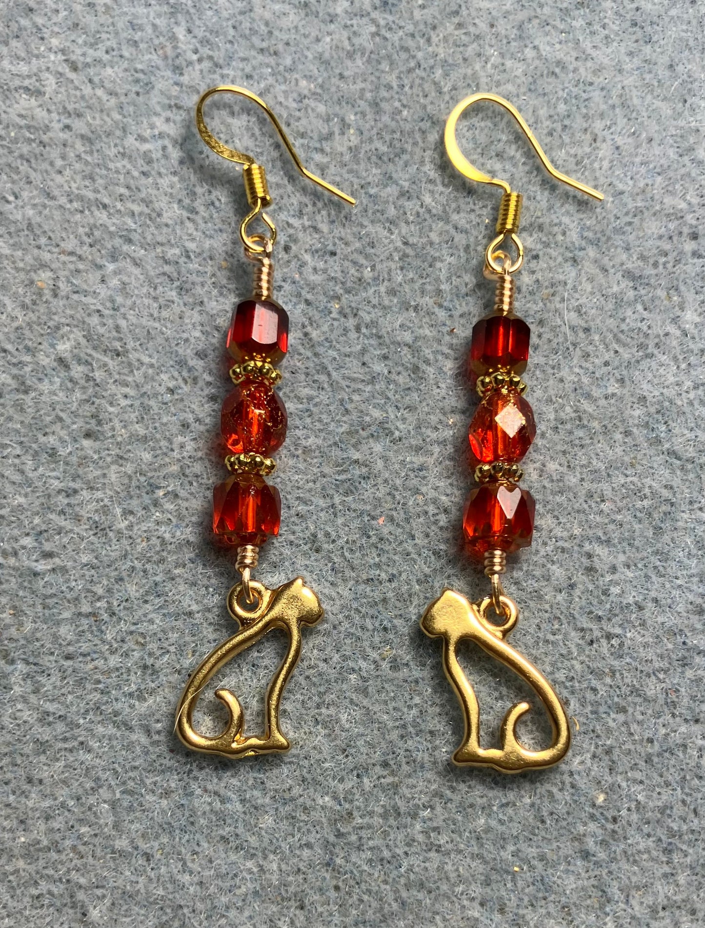 Gold silhouette cat charm earrings adorned with red Czech glass beads
