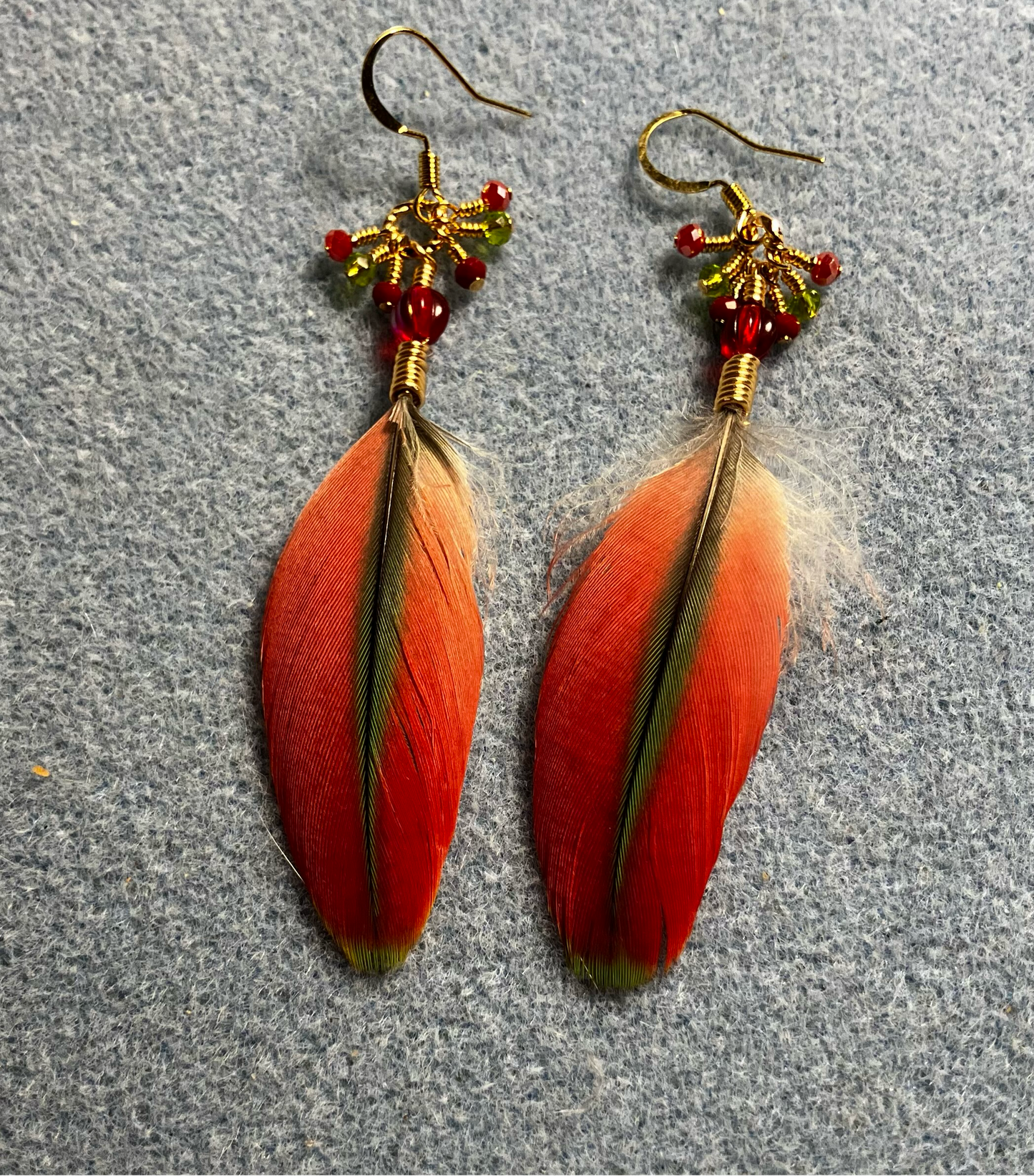 Small red and olive green Pionus feather earrings adorned with red Czech glass beads and tiny dangling red and olive green Chinese crystal beads.