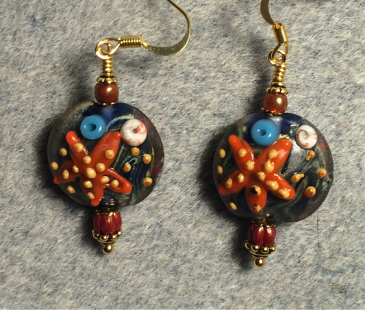 Blue and orange lamp work starfish bead earrings adorned with dark orange Czech glass beads.