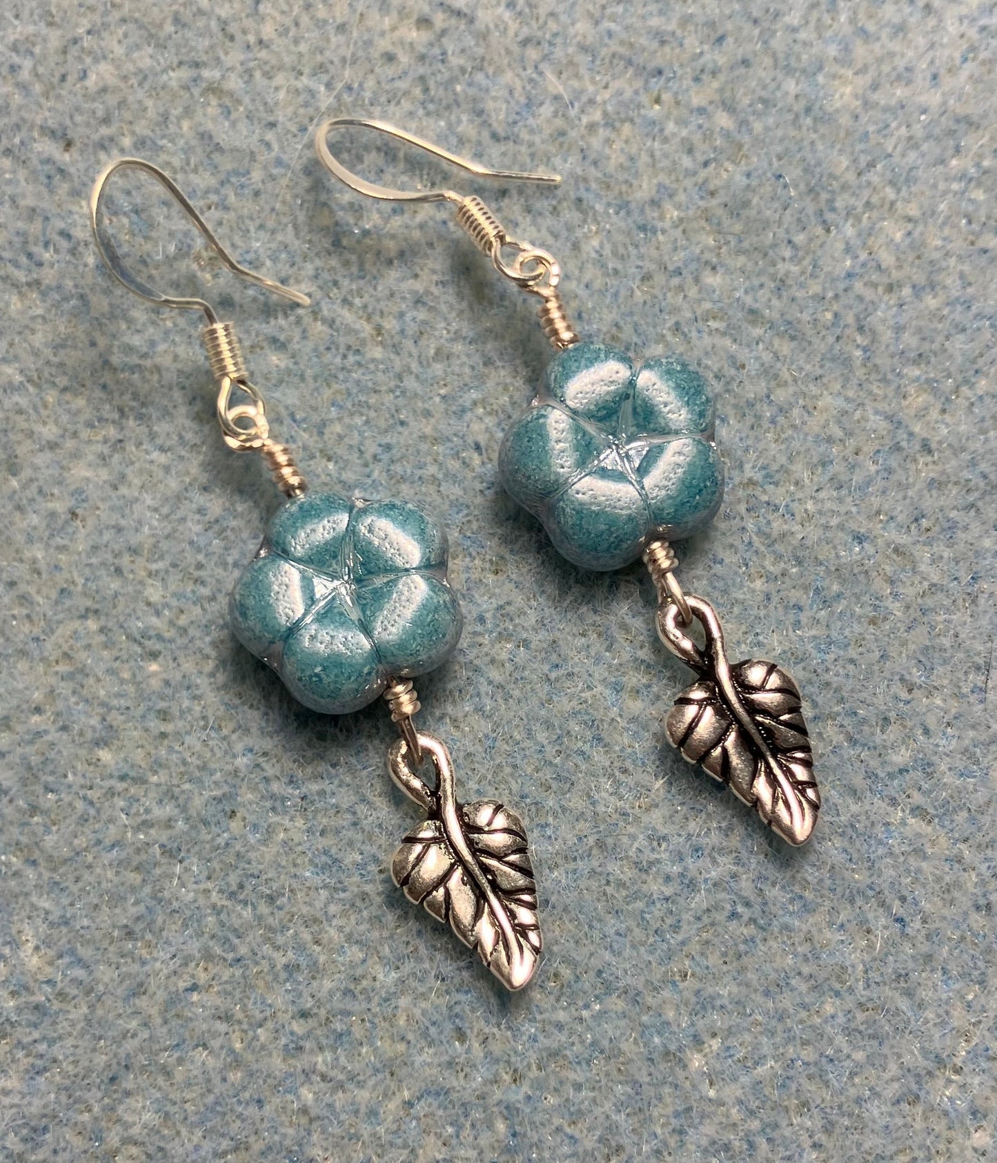 Light blue Czech glass puffy flower bead earrings adorned with silver Tierracast leaf charms.