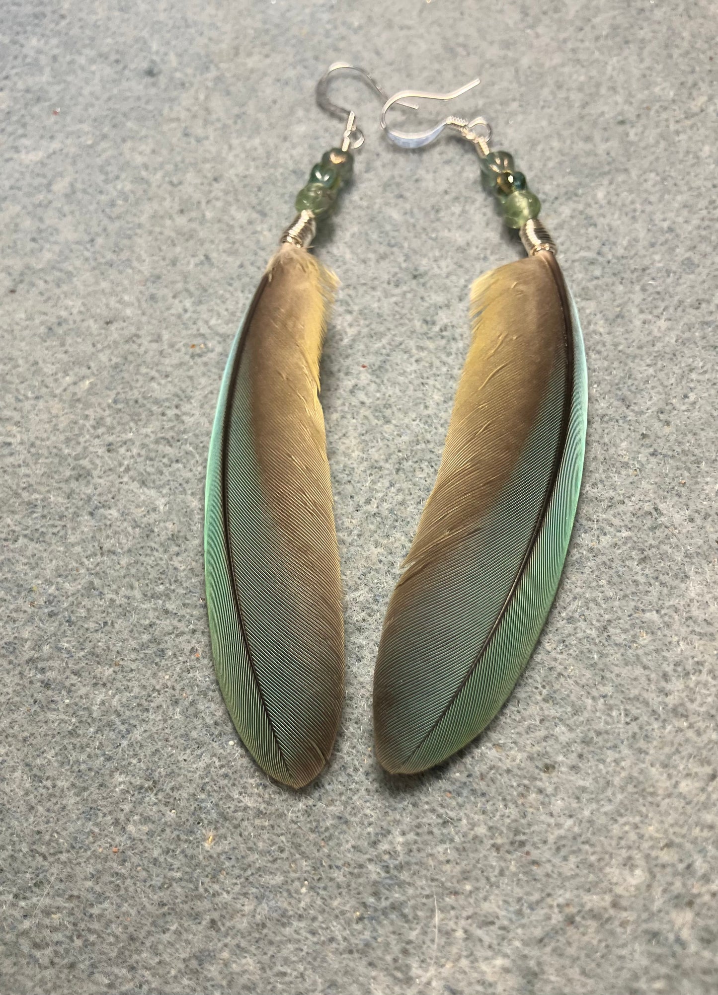 Small pointed green gray red-fronted macaw feather earrings adorned with small green gray Czech glass beads.