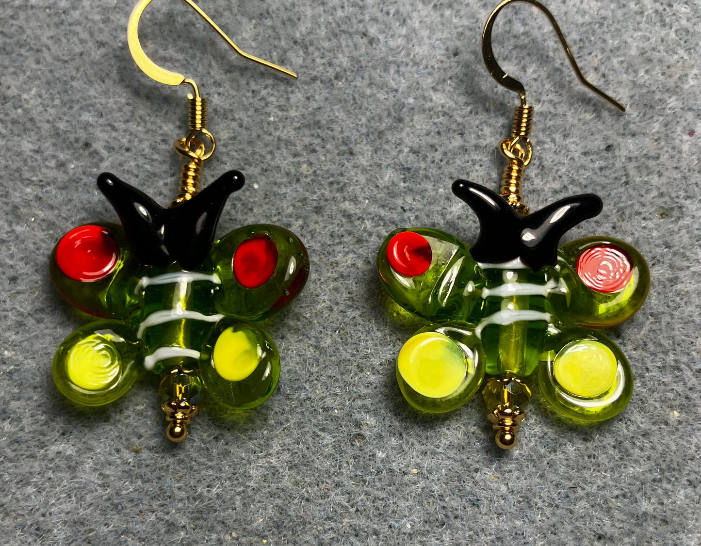 Olive green, red, yellow, and black lamp work butterfly bead earrings adorned with olive green Czech glass beads.