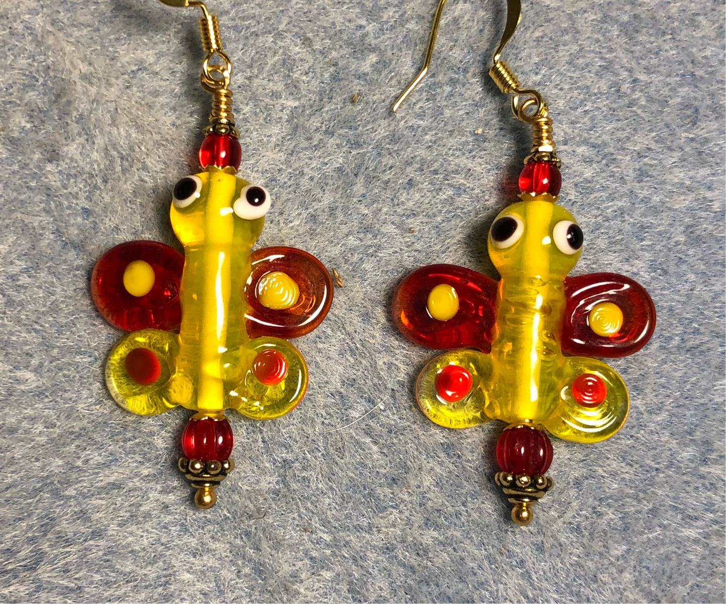 Red and yellow lamp work butterfly bead earrings adorned with red Czech glass beads.