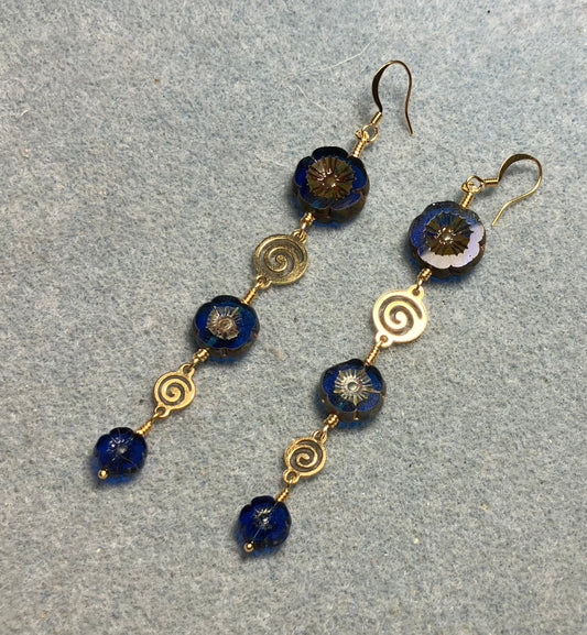Extra long blue flower bead earrings made with three sizes of cobalt blue Czech glass pansy beads joined by gold swirly connectors.