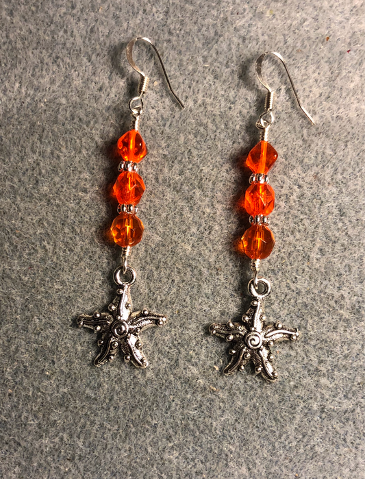 Silver starfish charm earrings adorned with orange Czech glass beads.