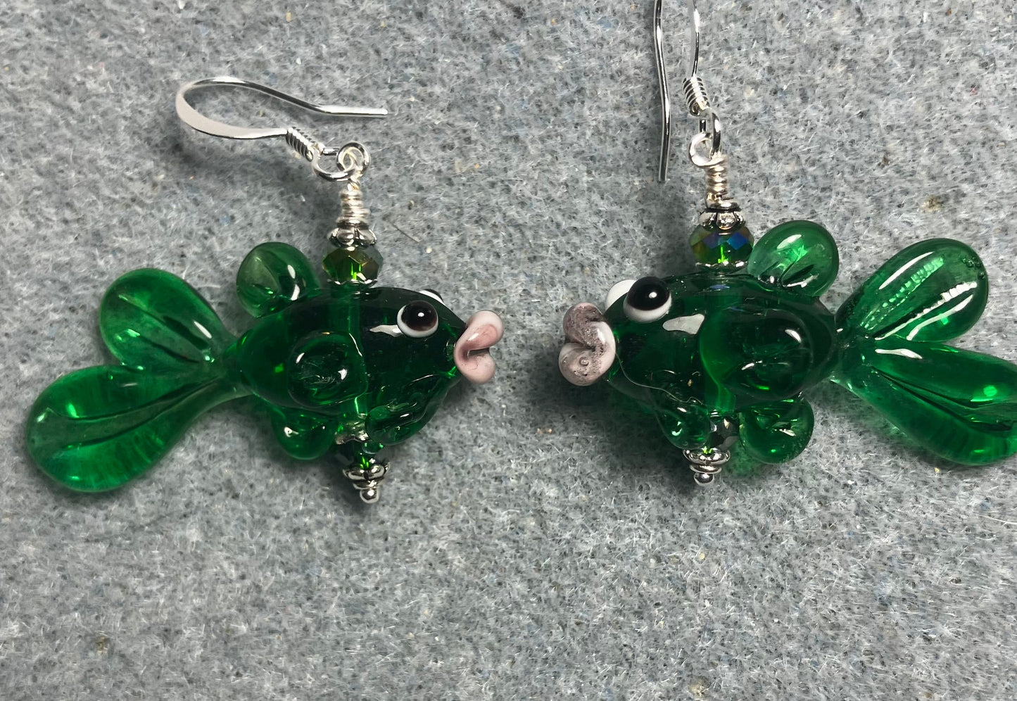 Translucent emerald green lamp work fish bead earrings adorned with emerald green Chinese crystal beads.