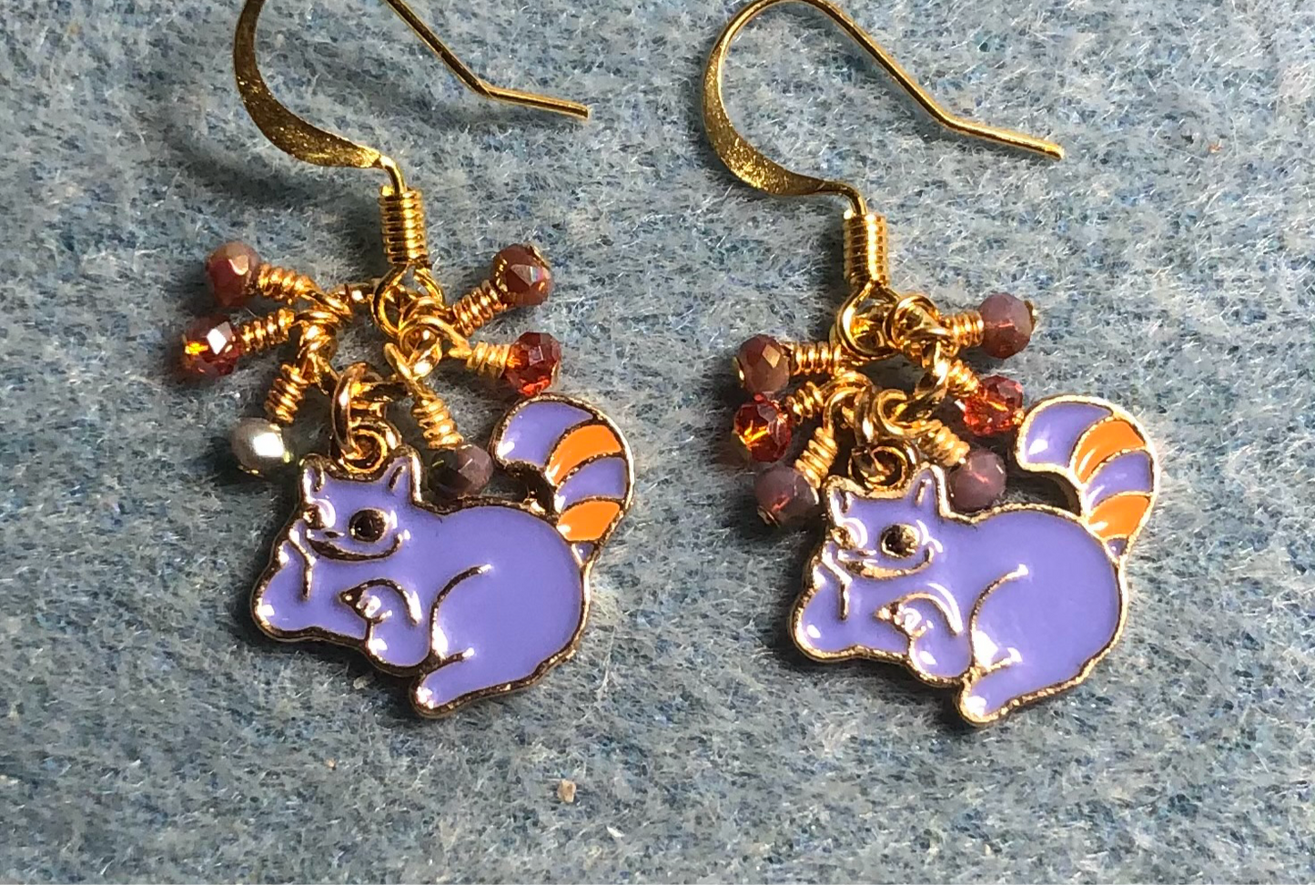 Small violet and orange enamel Cheshire Cat charm earrings adorned with tiny dangling violet and orange Chinese crystal beads.