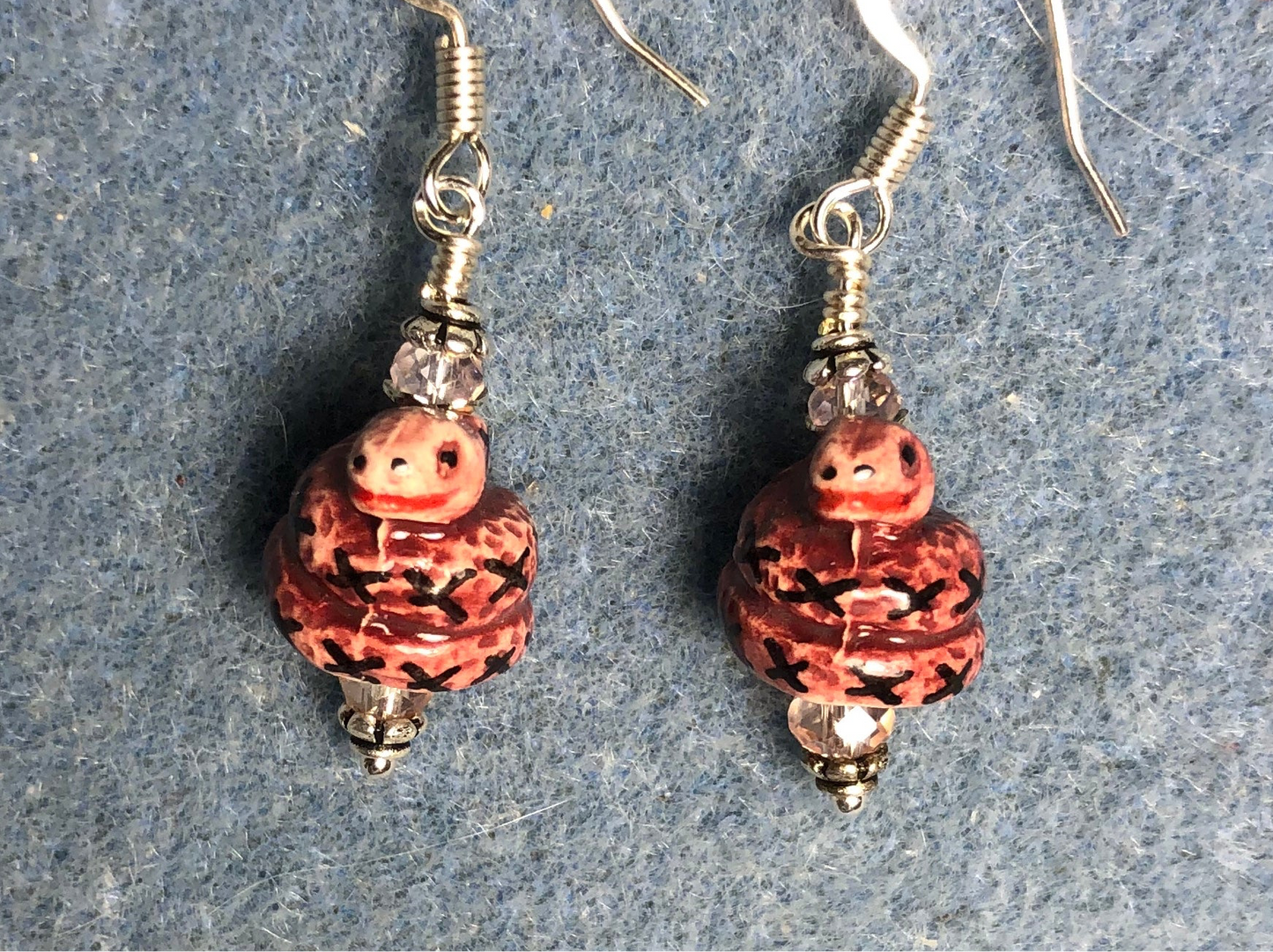 Small rose pink and black ceramic coiled snake bead earrings adorned with pink Chinese crystal beads.