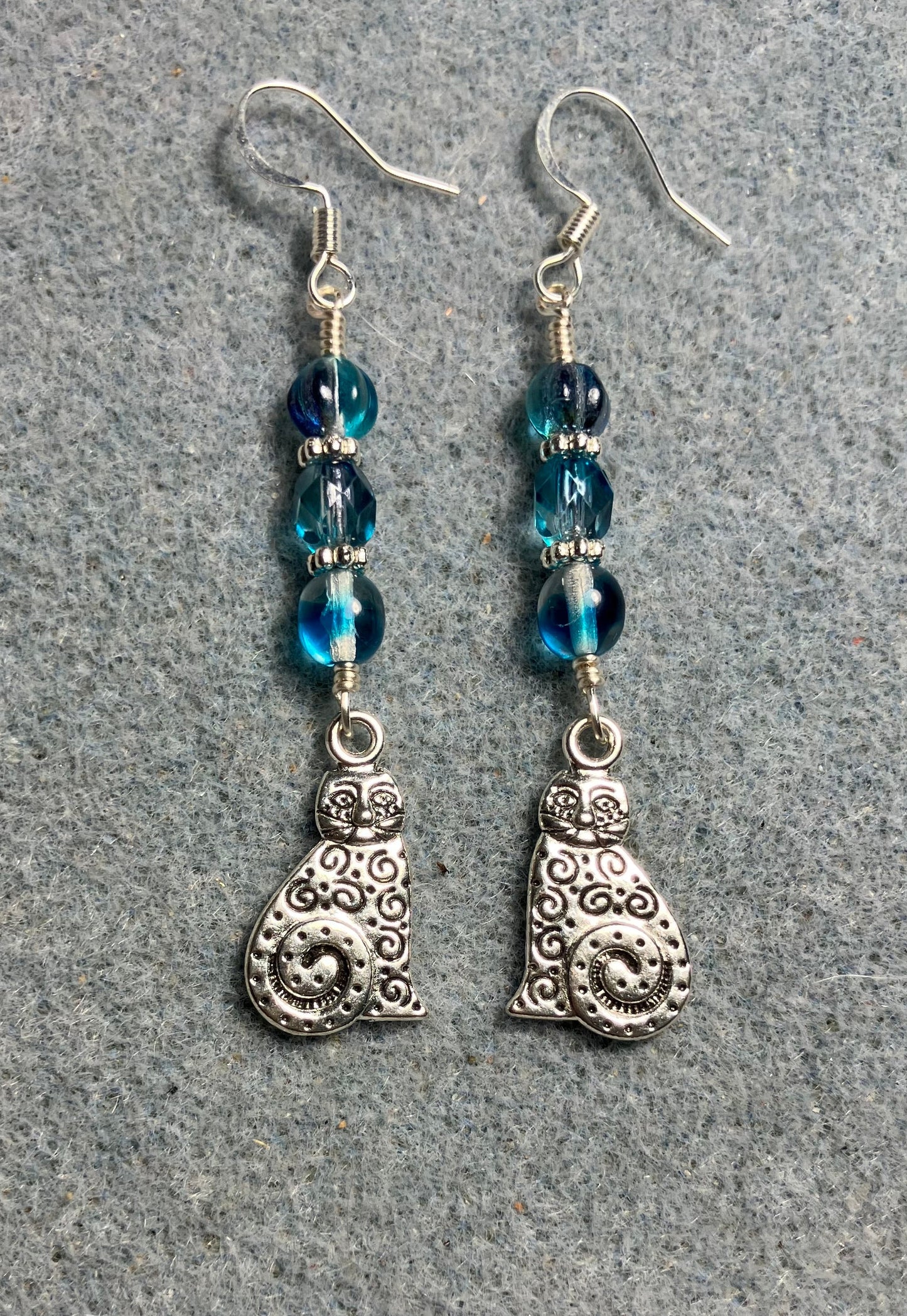 Silver swirly tailed cat charm earrings adorned with turquoise Czech glass beads