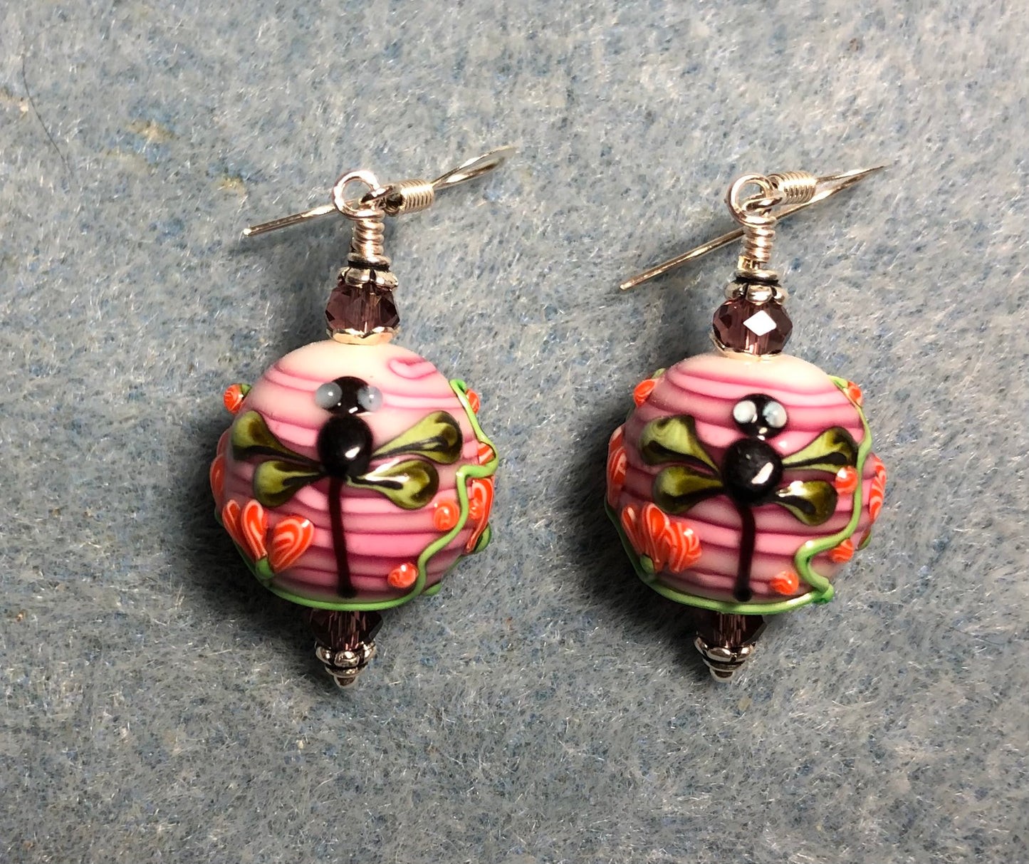 Violet pink, black, and green lamp work dragonfly bead earrings adorned with violet Chinese crystal beads.