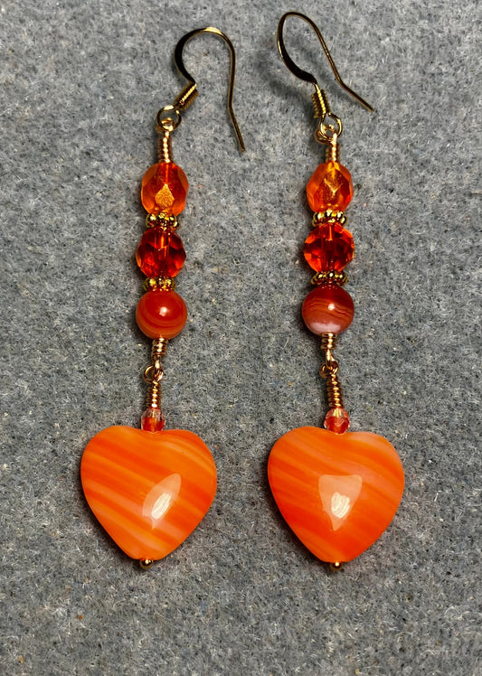 Opaque striped orange Czech glass heart bead earrings adorned with orange Czech glass beads.