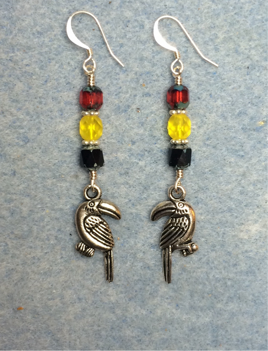 Silver toucan charm earrings adorned with black, yellow, and red Czech glass beads