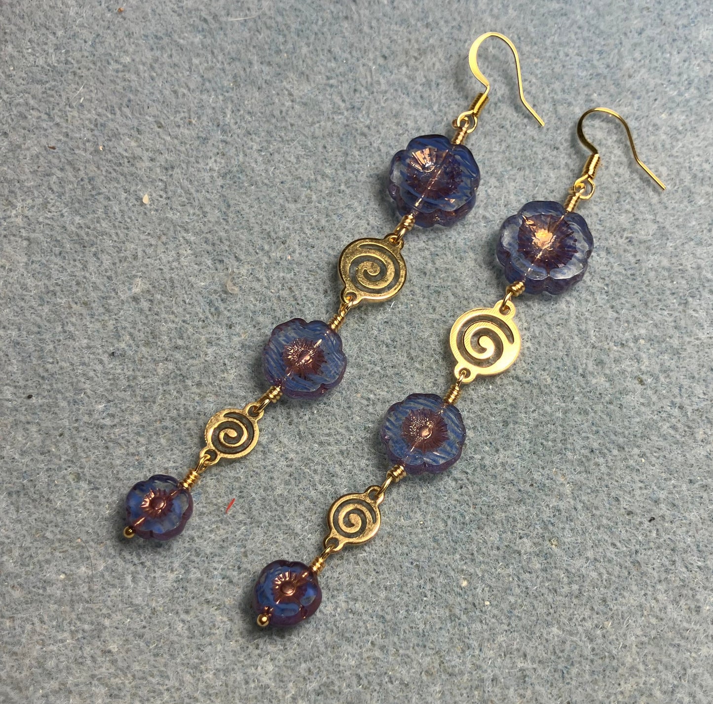 Extra long blue striped flower bead earrings made with three sizes of blue striped Czech glass pansy beads joined by gold swirly connectors.