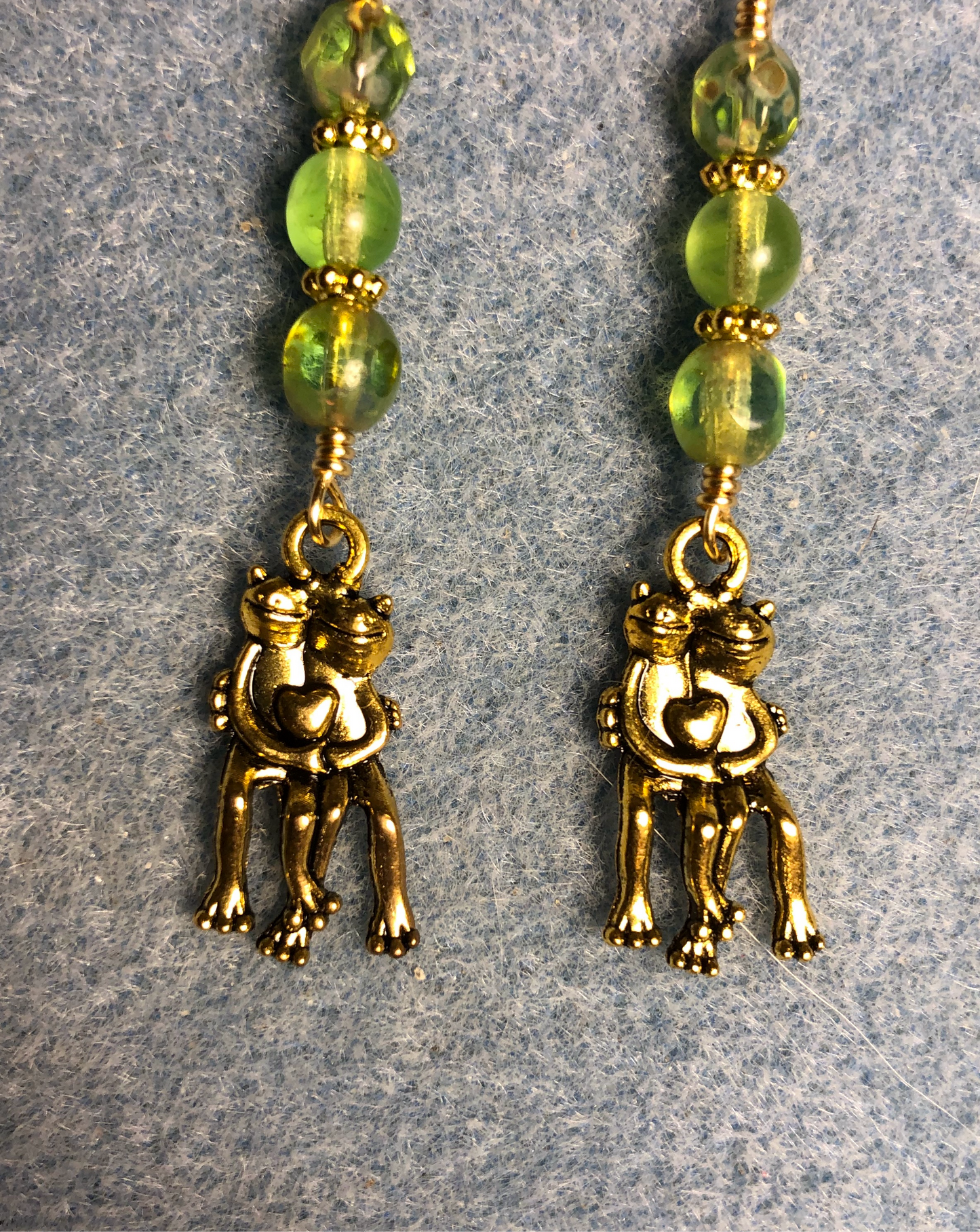 Gold pair of hugging frog charm earrings adorned with lime green Czech glass beads