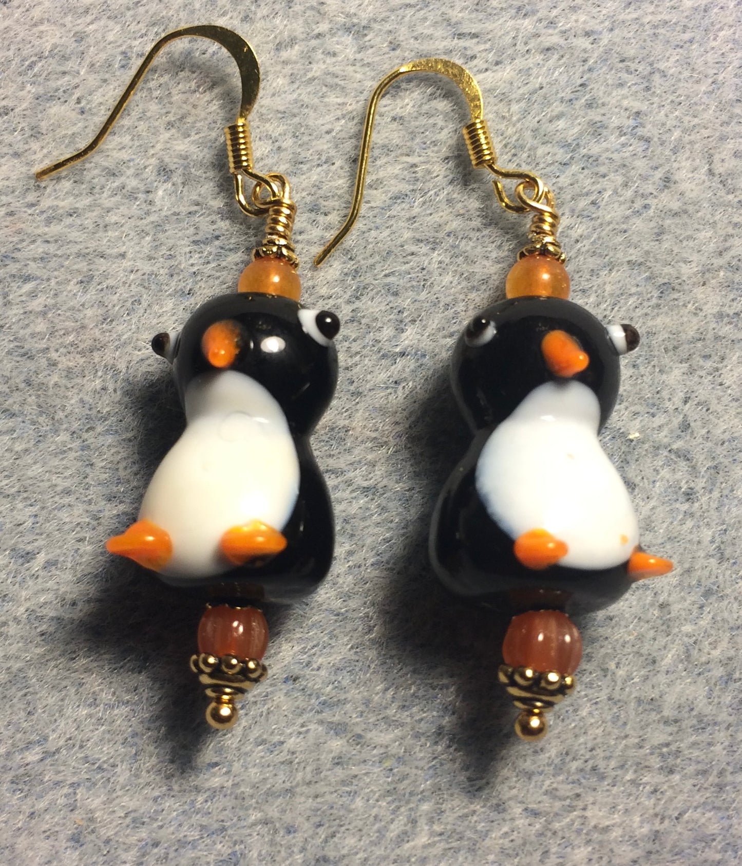 Black, white, and orange lamp work penguin bead earrings adorned with orange Czech glass beads.