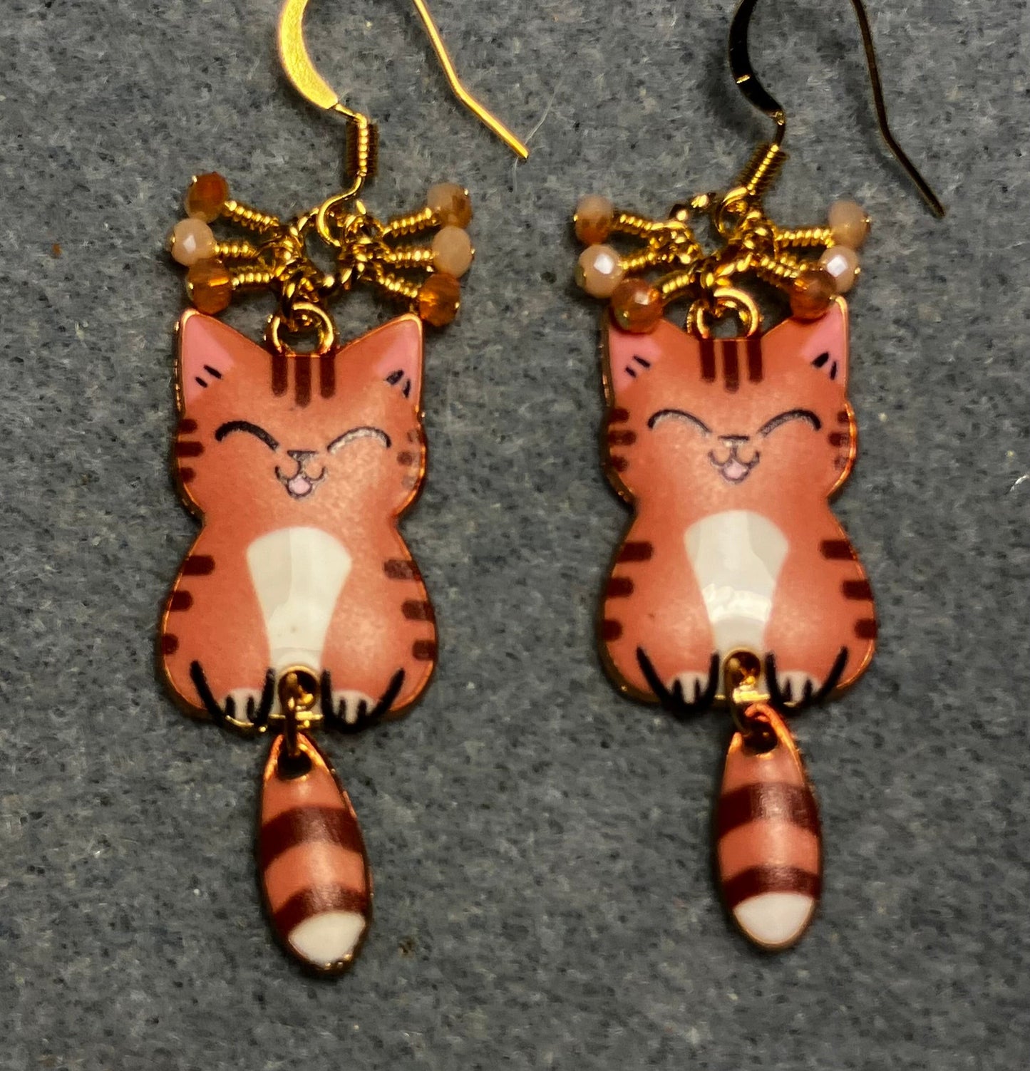 Orange, brown, and white enamel tabby cat charm earrings adorned with tiny dangling orange and white Chinese crystal beads.