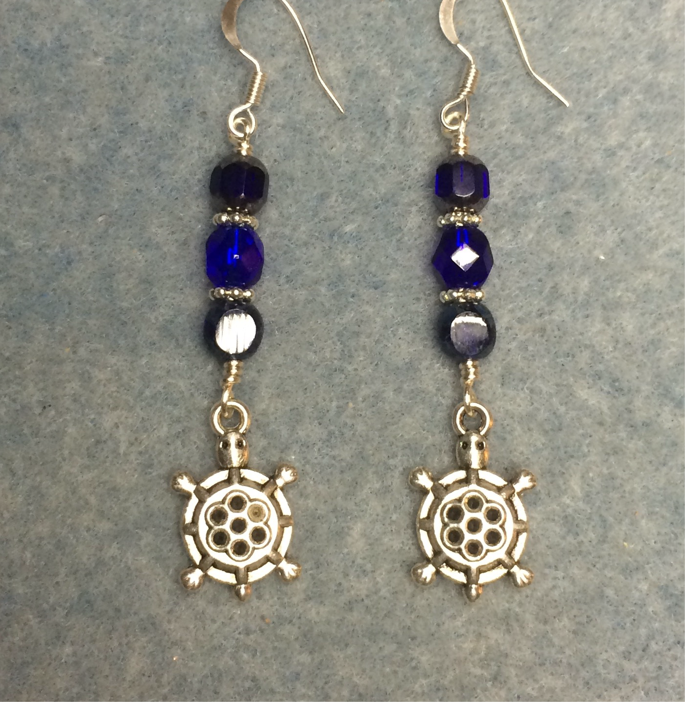 Silver turtle charm earrings adorned with dark blue Czech glass beads.