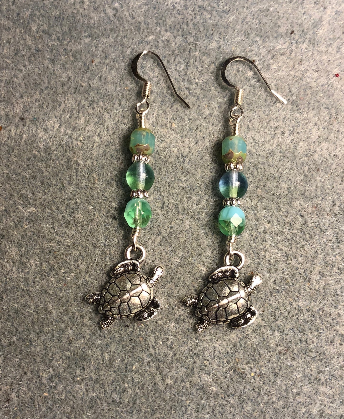 Silver Tierracast sea turtle charm earrings adorned with light green Czech glass beads