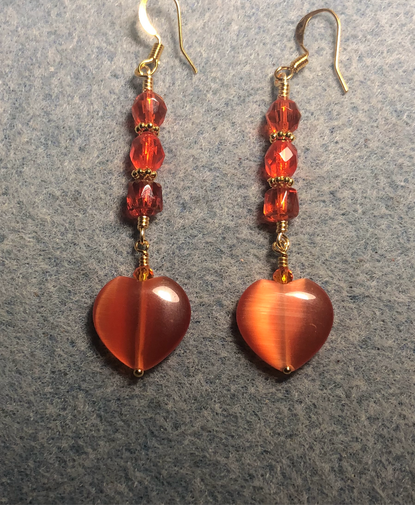 Orange fiber optic (cat’s eye) Czech glass heart bead earrings adorned with orange Czech glass beads.