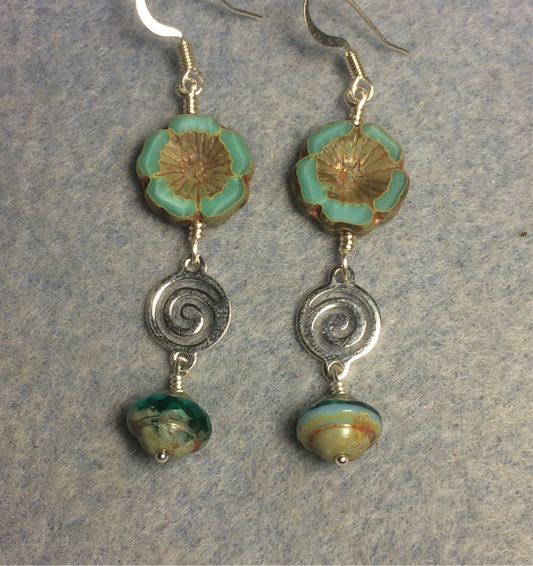 Turquoise green Czech glass pansy bead earrings adorned with silver swirly connectors and turquoise green Czech glass Saturn beads.