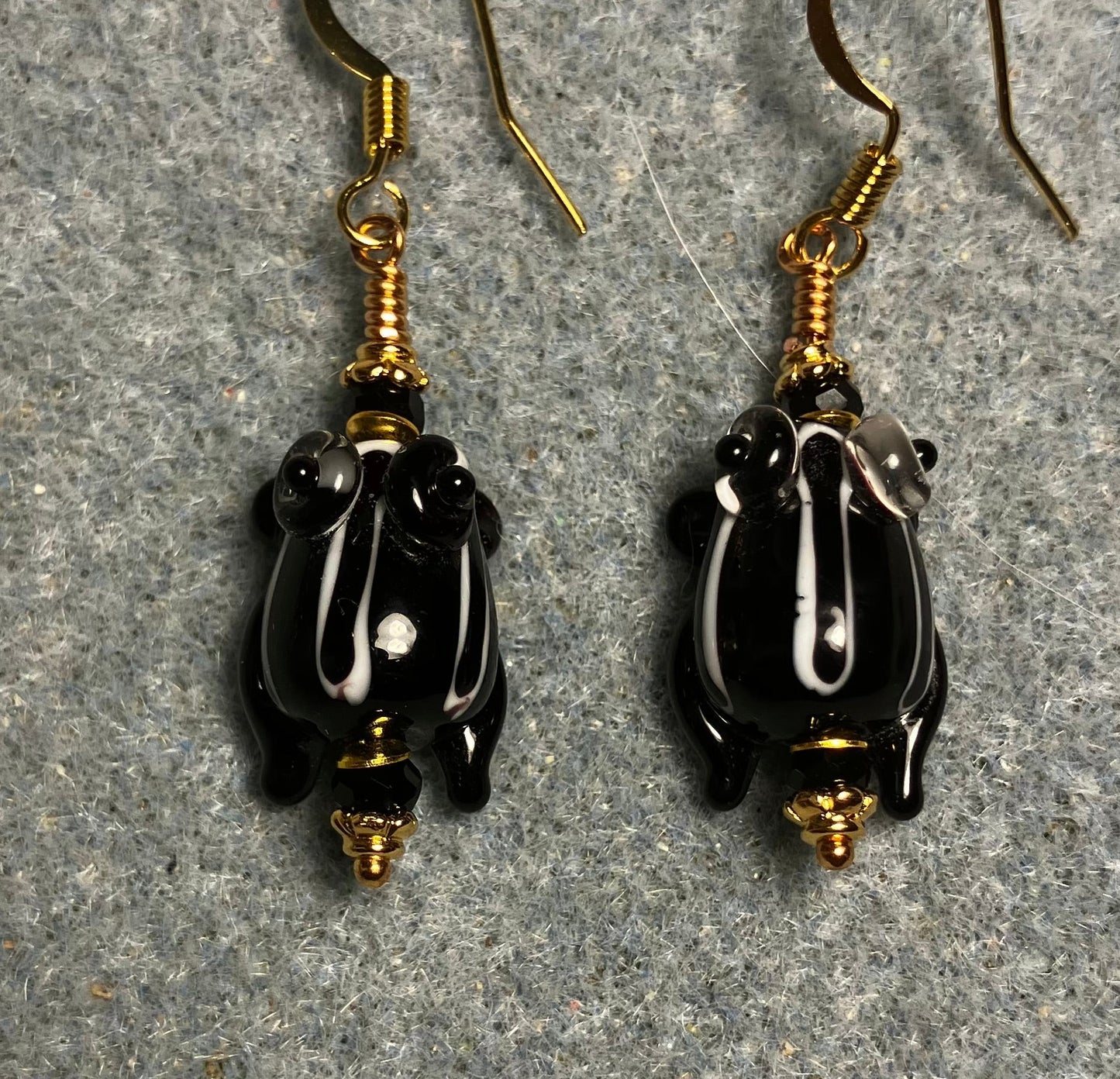 Very small black with white stripes lamp work frog bead earrings adorned with black Chinese crystal beads.