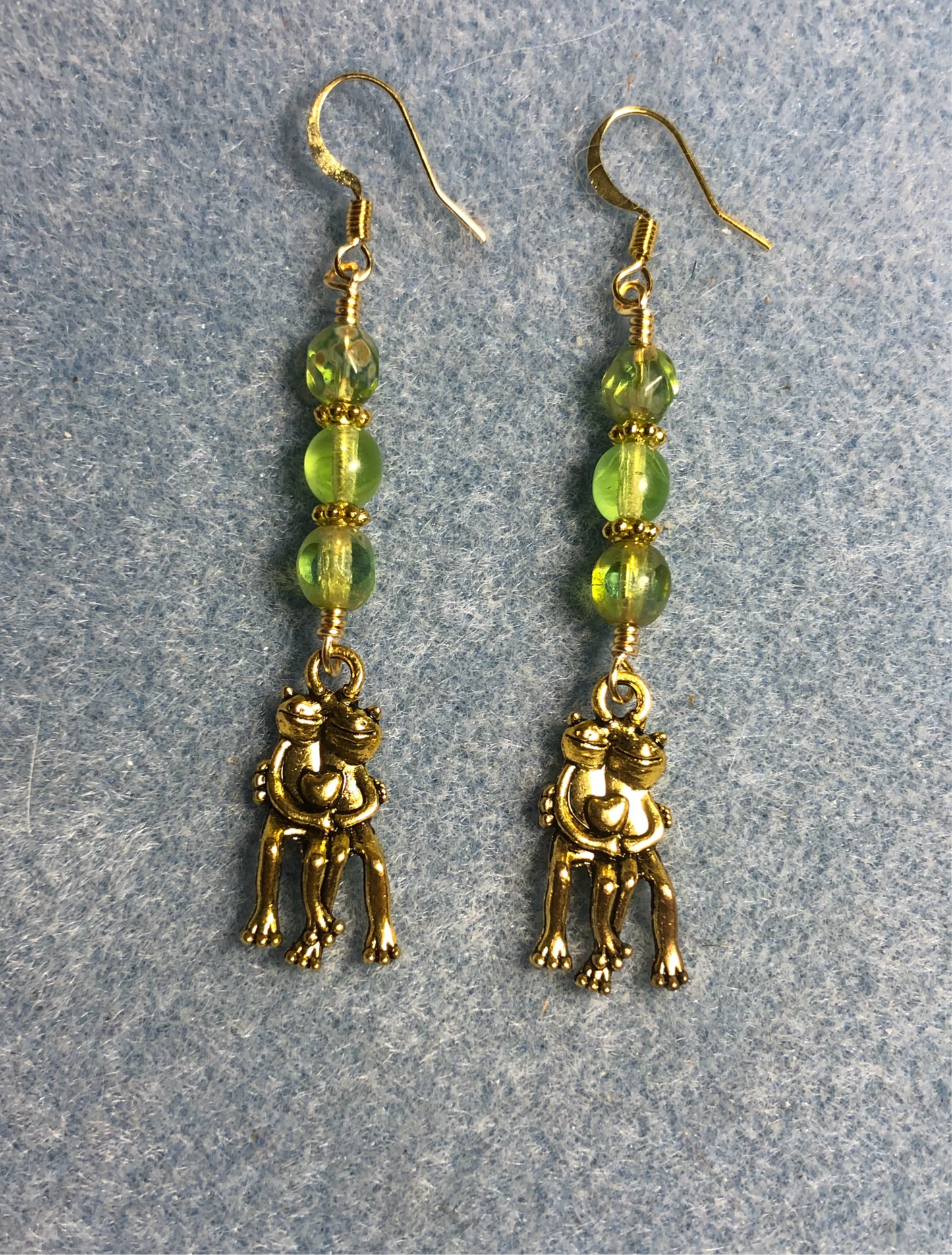 Gold pair of hugging frog charm earrings adorned with lime green Czech glass beads