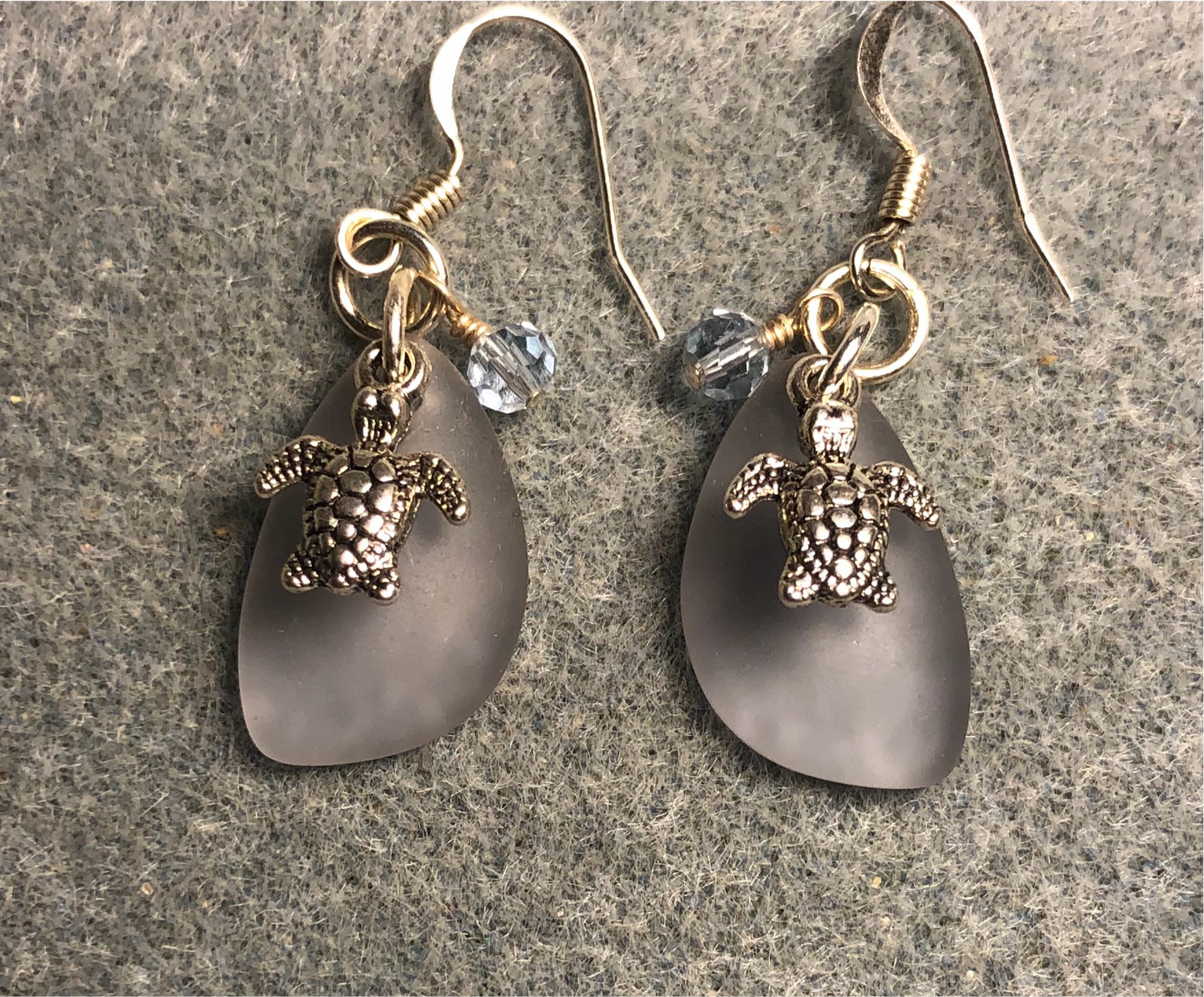 Small light blue sea glass pendant bead earrings adorned with small silver sea turtle charms and light light Chinese crystal beads.