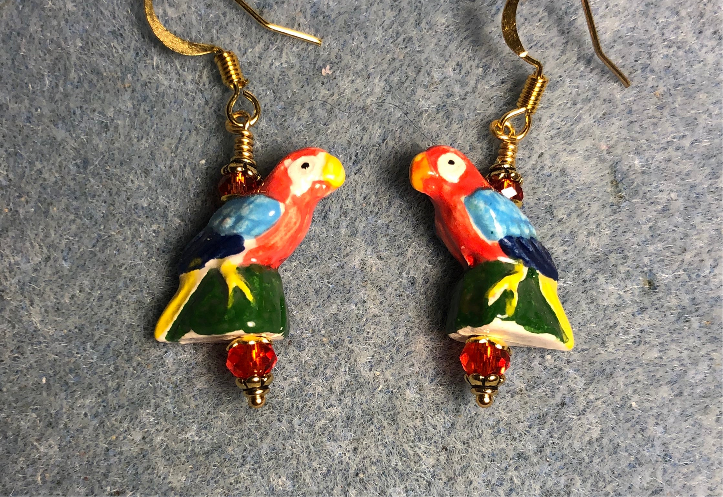 Small red, blue, and green ceramic parrot bead earrings adorned with red Chinese crystal beads.