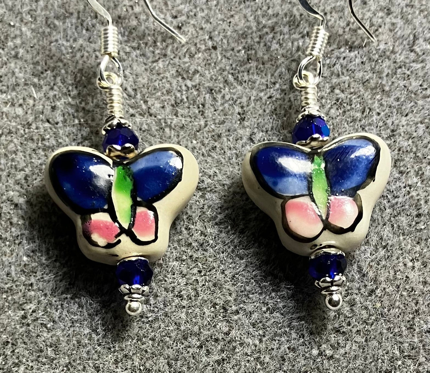 Dark blue, pink, and green ceramic butterfly bead earrings adorned with dark blue Chinese crystal beads.