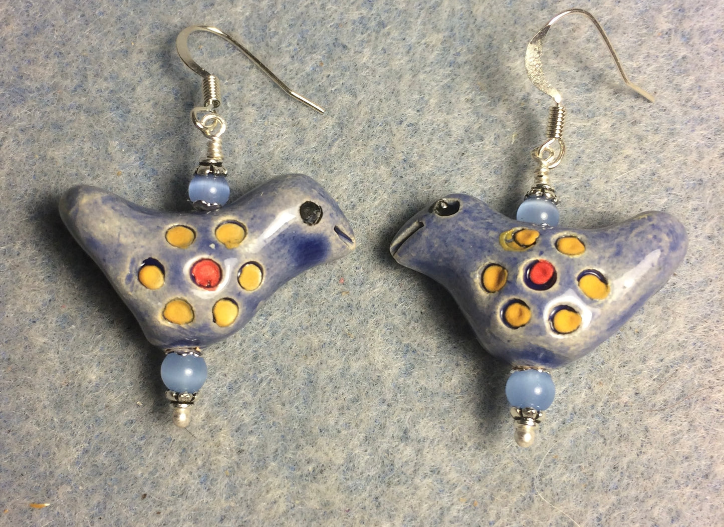 Medium blue, yellow, and red ceramic songbird bead earrings adorned with blue Czech glass beads.