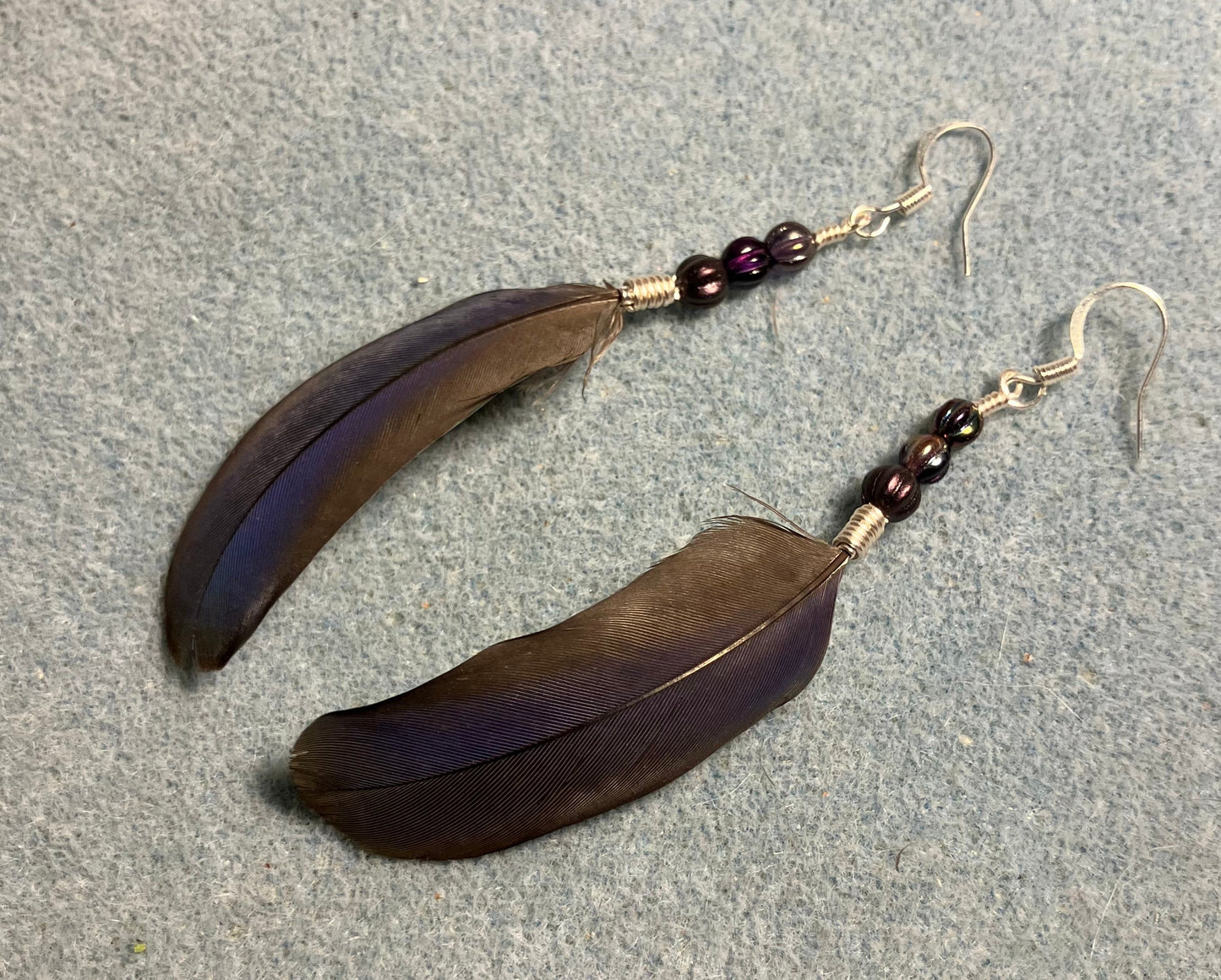 Purple Pionus parrot feather earrings adorned with small purple Czech glass melon beads.