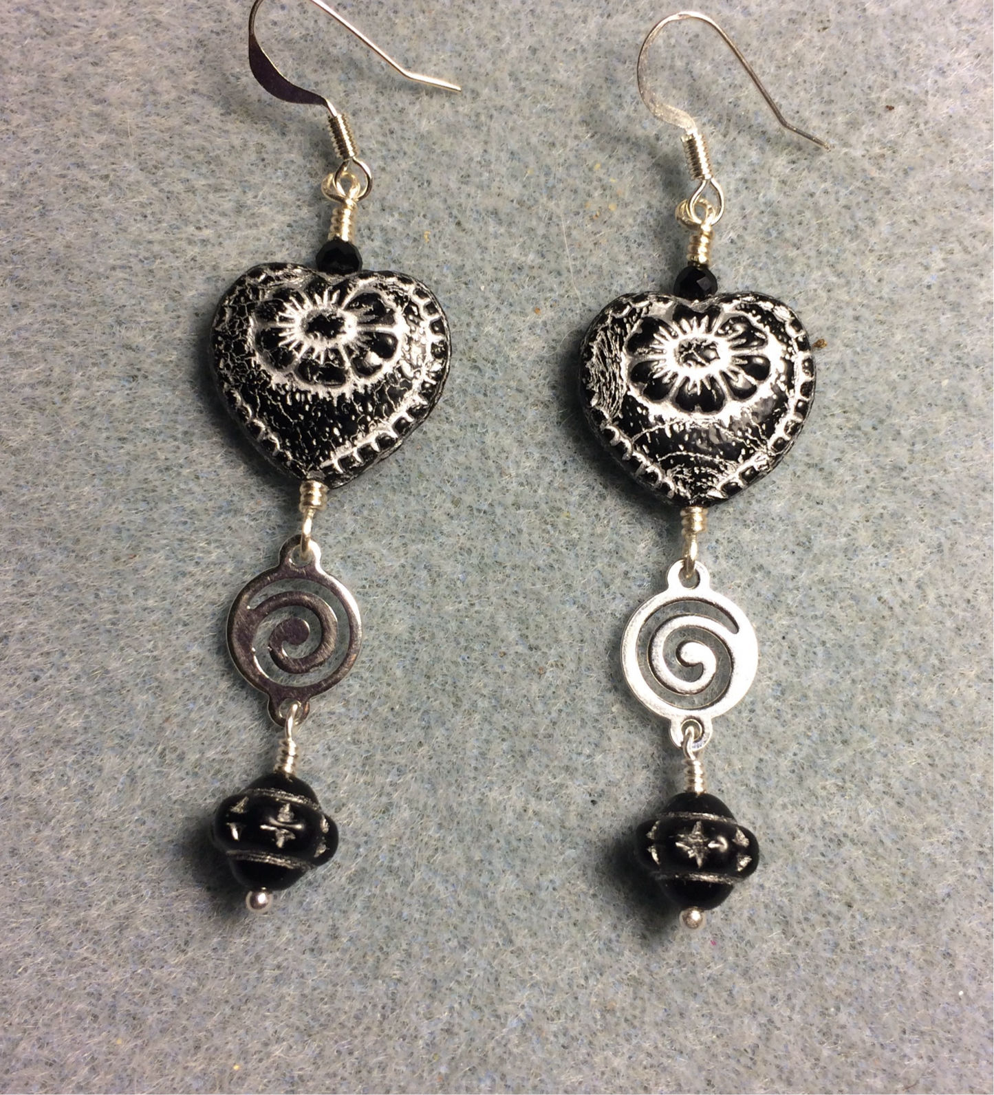 Opaque black (with silver inlay) Czech glass heart bead earrings adorned with silver swirly links and black Czech glass Saturn beads.
