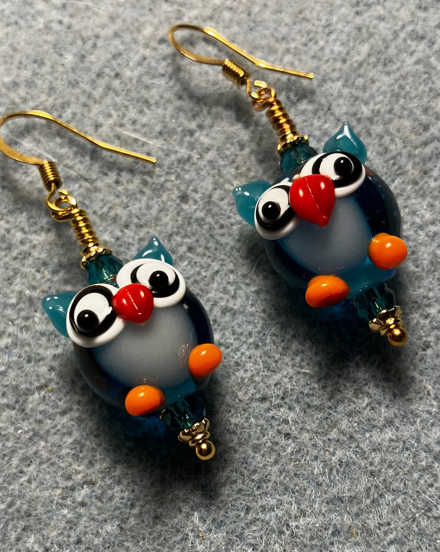 Turquoise, orange, and red lamp work owl bead earrings adorned with turquoise Chinese crystal beads.