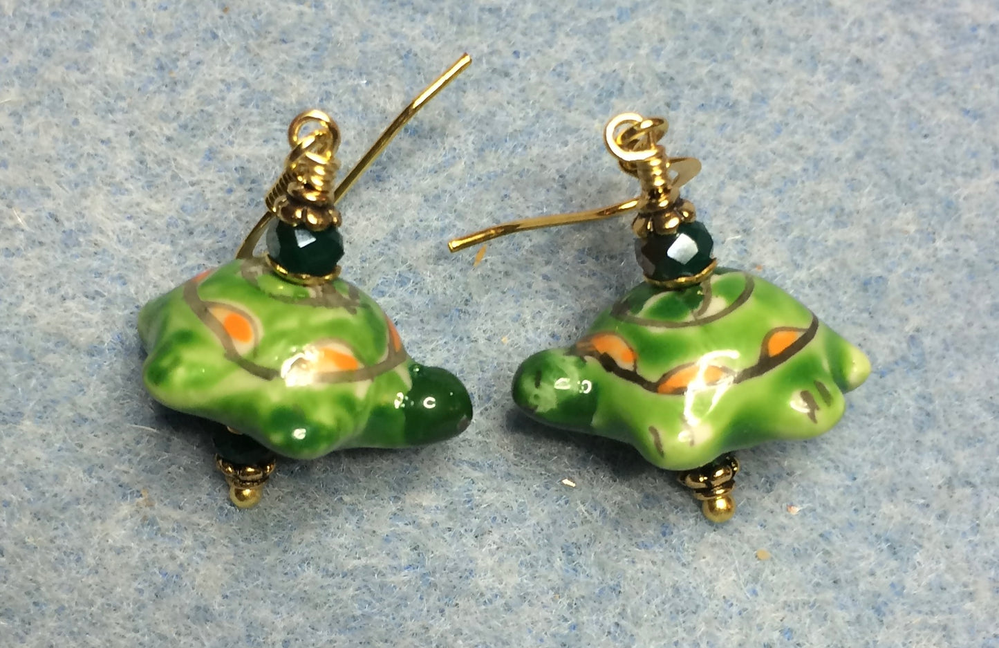 Green and orange ceramic turtle bead earrings adorned with dark green Chinese crystal beads.