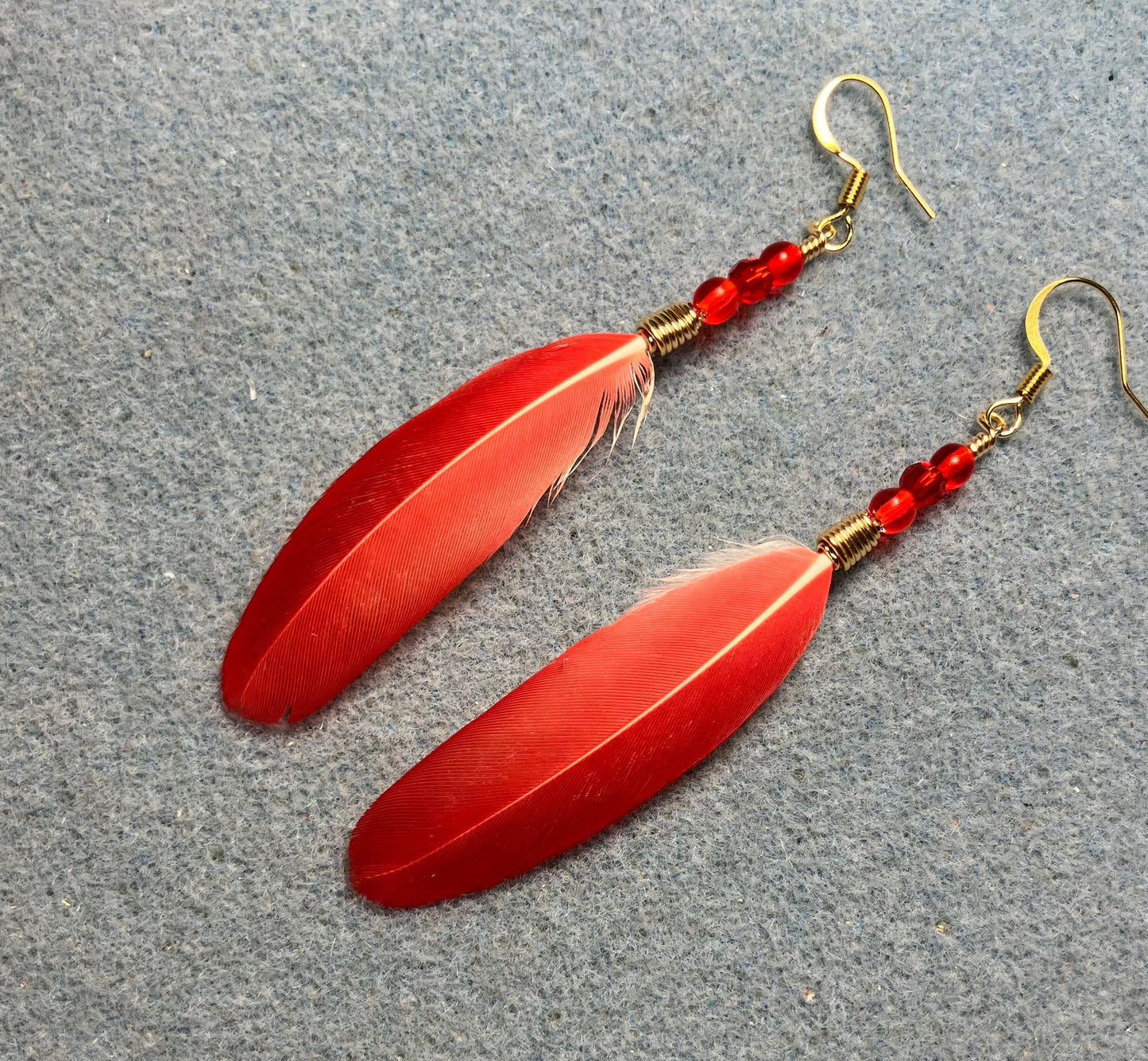 Bright red spectacled Amazon feather earrings adorned with small red Czech glass beads.