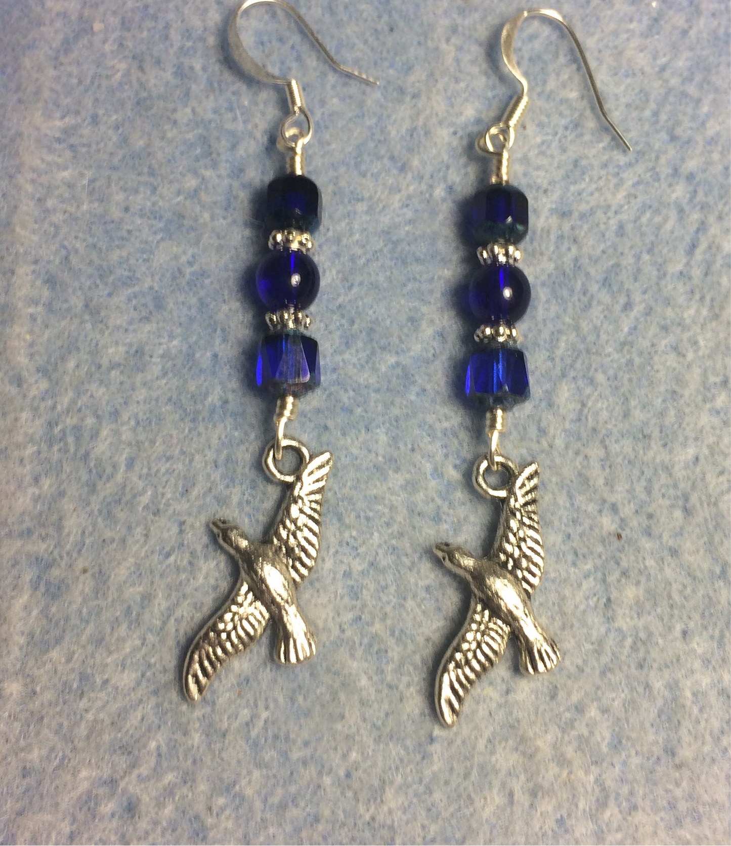 Silver flying bird charm earrings adorned with dark blue Czech glass beads