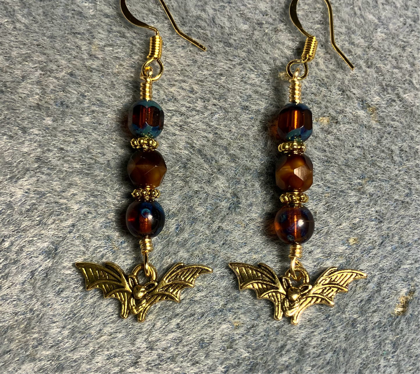 Small gold bat charm earrings adorned with blue Czech glass beads