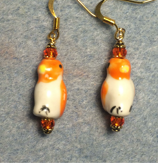 Orange and white ceramic penguin bead earrings adorned with orange Chinese crystal beads.