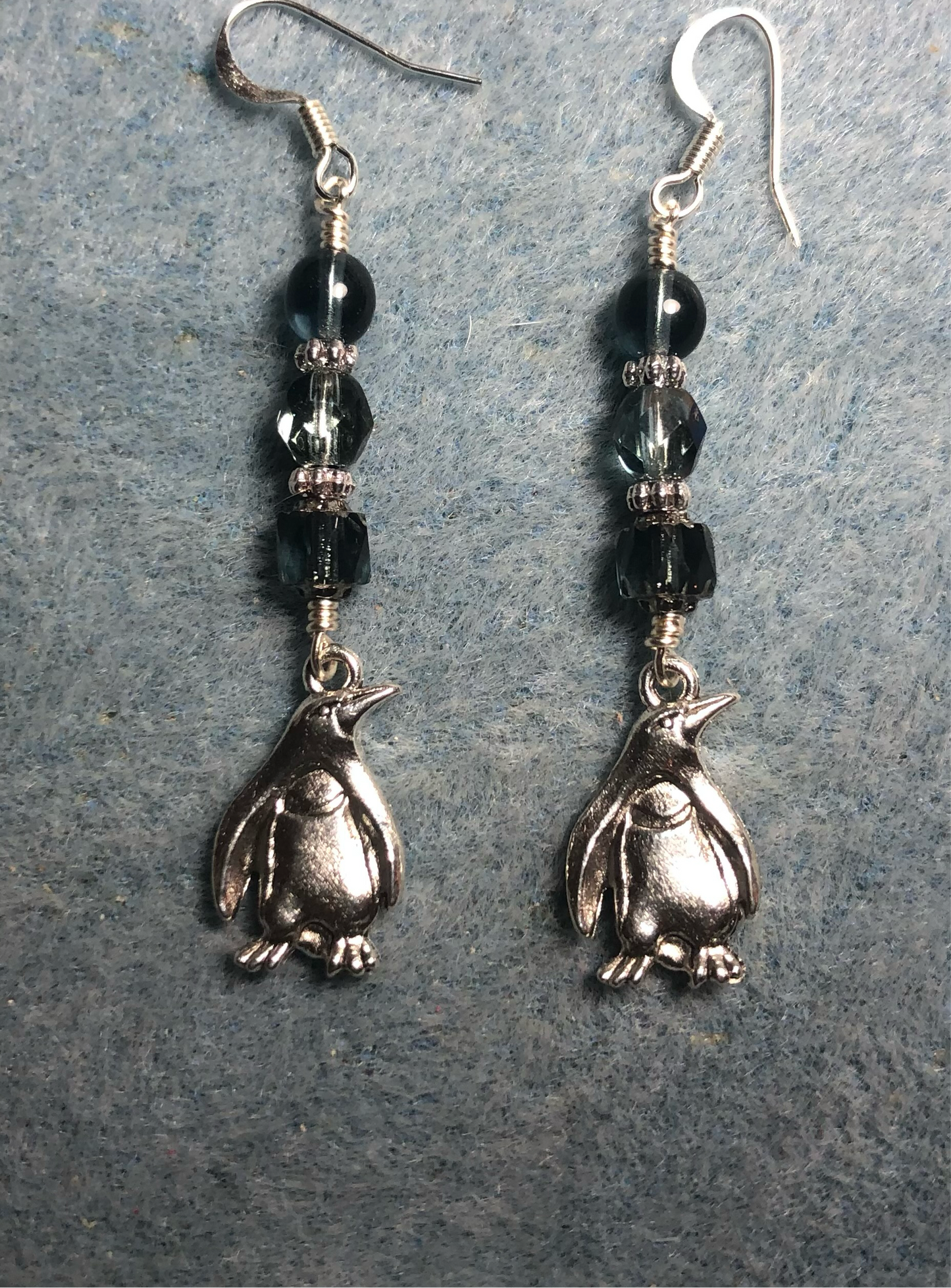 Silver penguin charm earrings adorned with dark gray Czech glass beads.