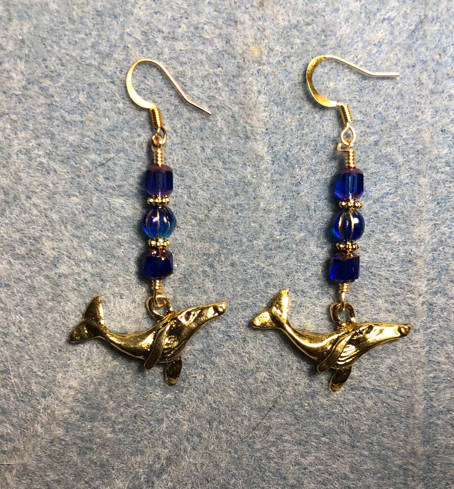 Gold humpback whale charm earrings adorned with dark blue Czech glass beads