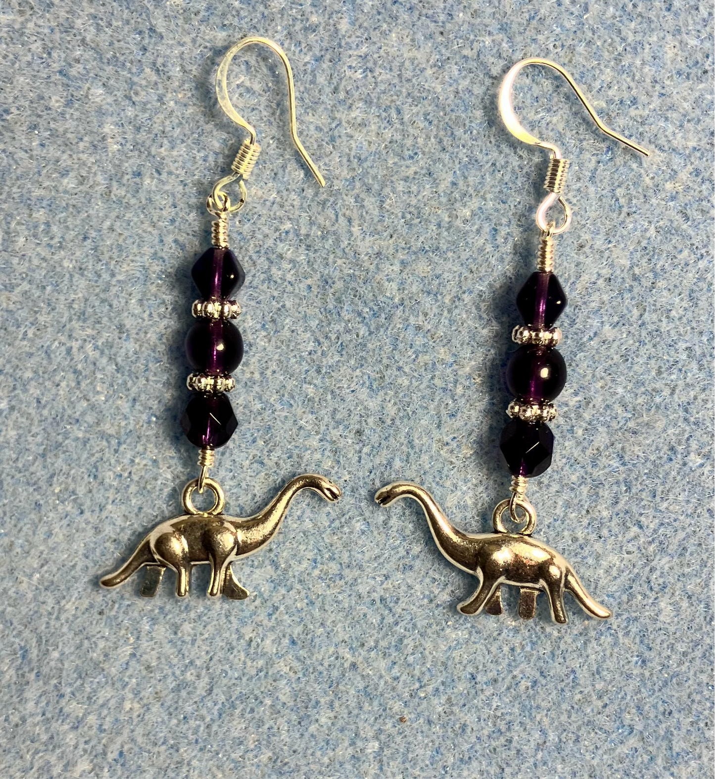 Silver brontosaurus charm earrings adorned with grape purple Czech glass beads.