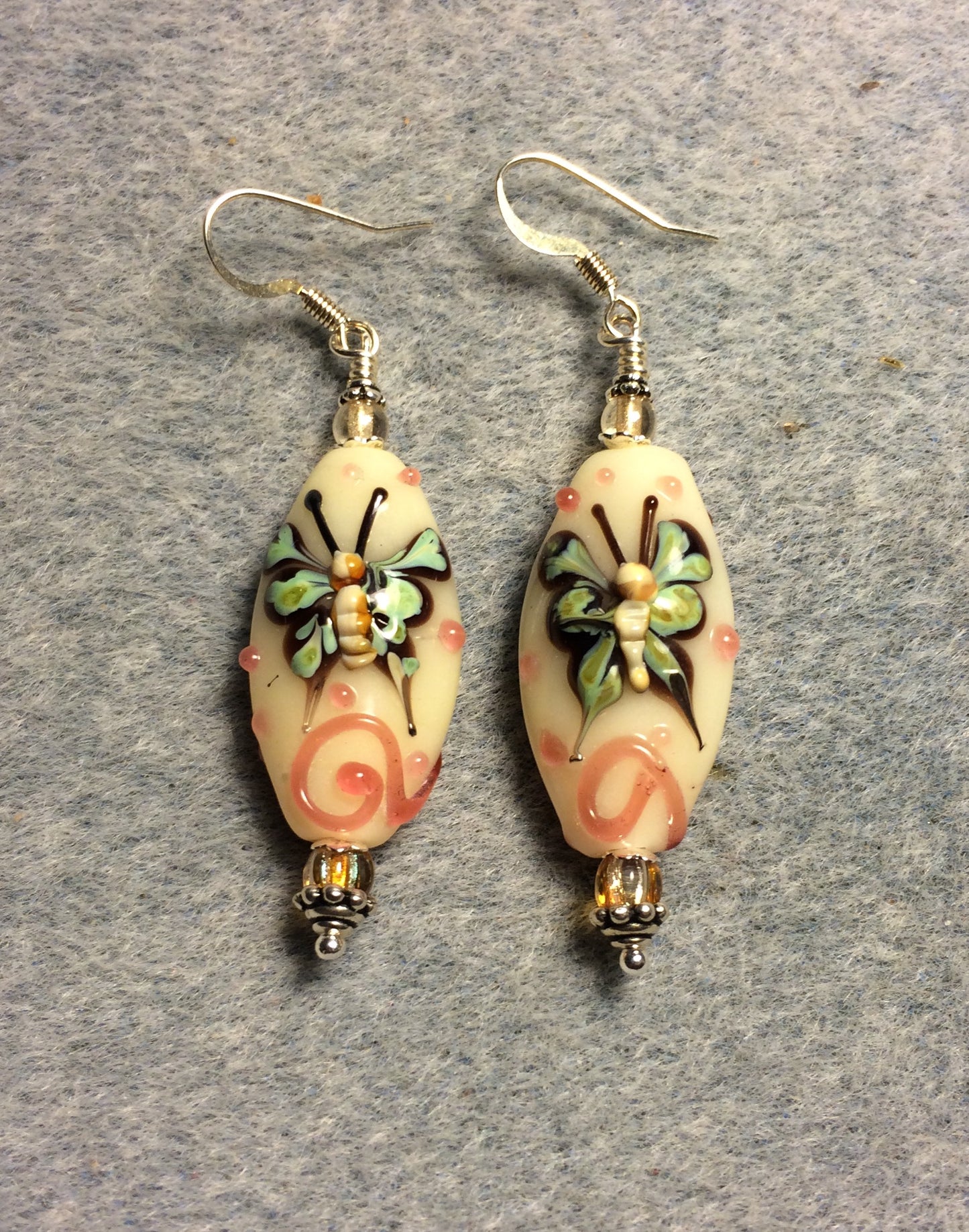 Tan, coral, and green lamp work butterfly bead earrings adorned with tan Czech glass beads.