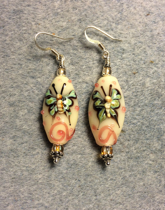 Tan, coral, and green lamp work butterfly bead earrings adorned with tan Czech glass beads.