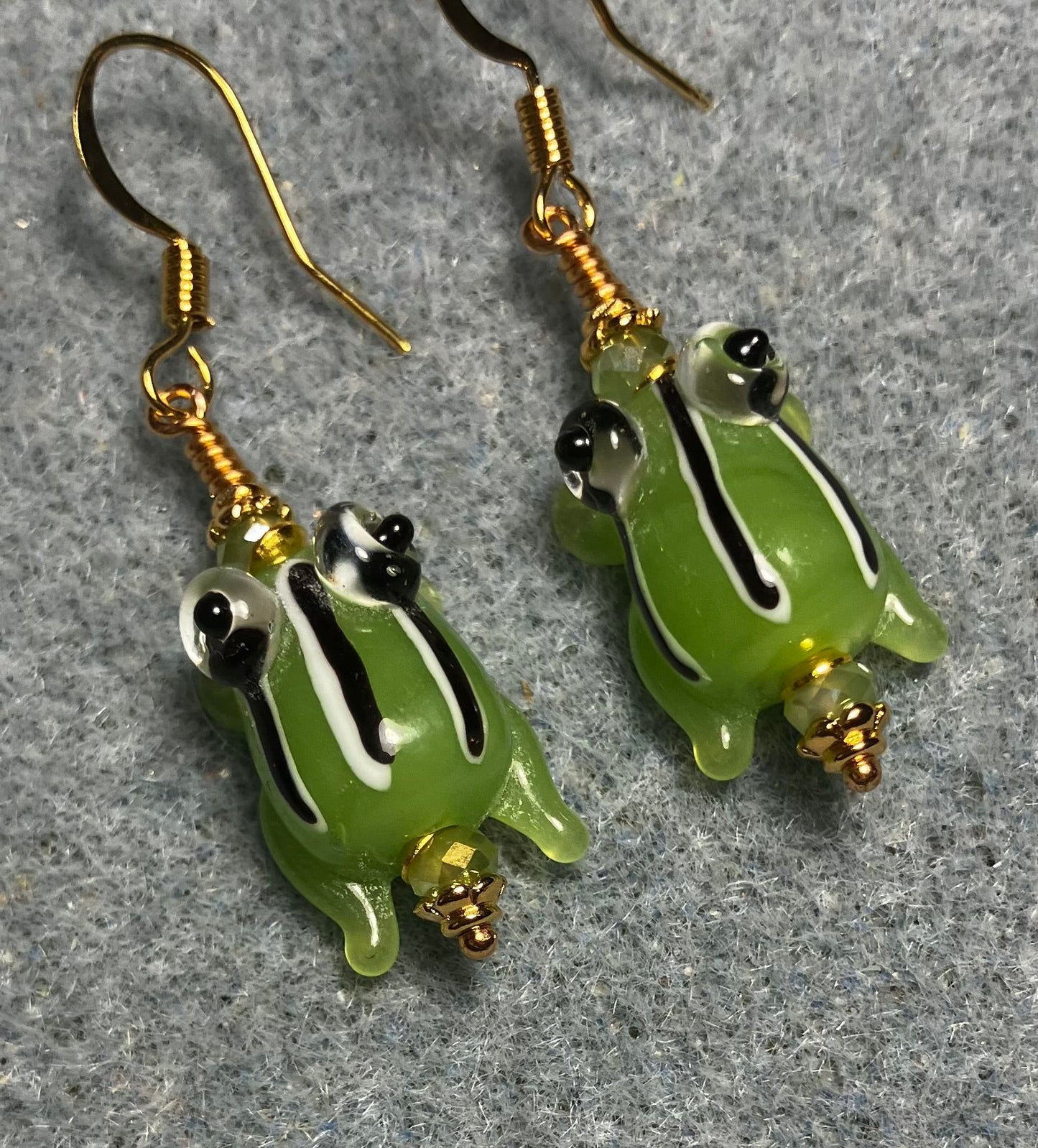 Very small opaque olive green with black and white stripes lamp work frog bead earrings adorned with olive green Chinese crystal beads.