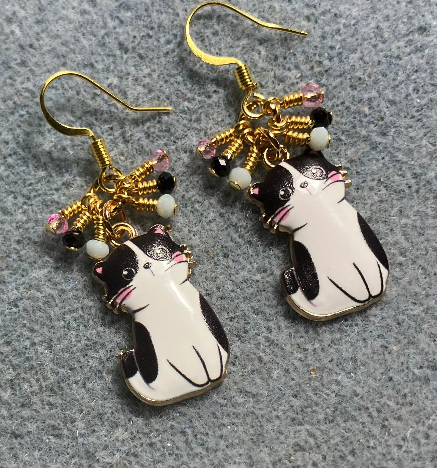 Black and white enamel cat charm earrings adorned with tiny dangling black, white, and pink Chinese crystal beads.