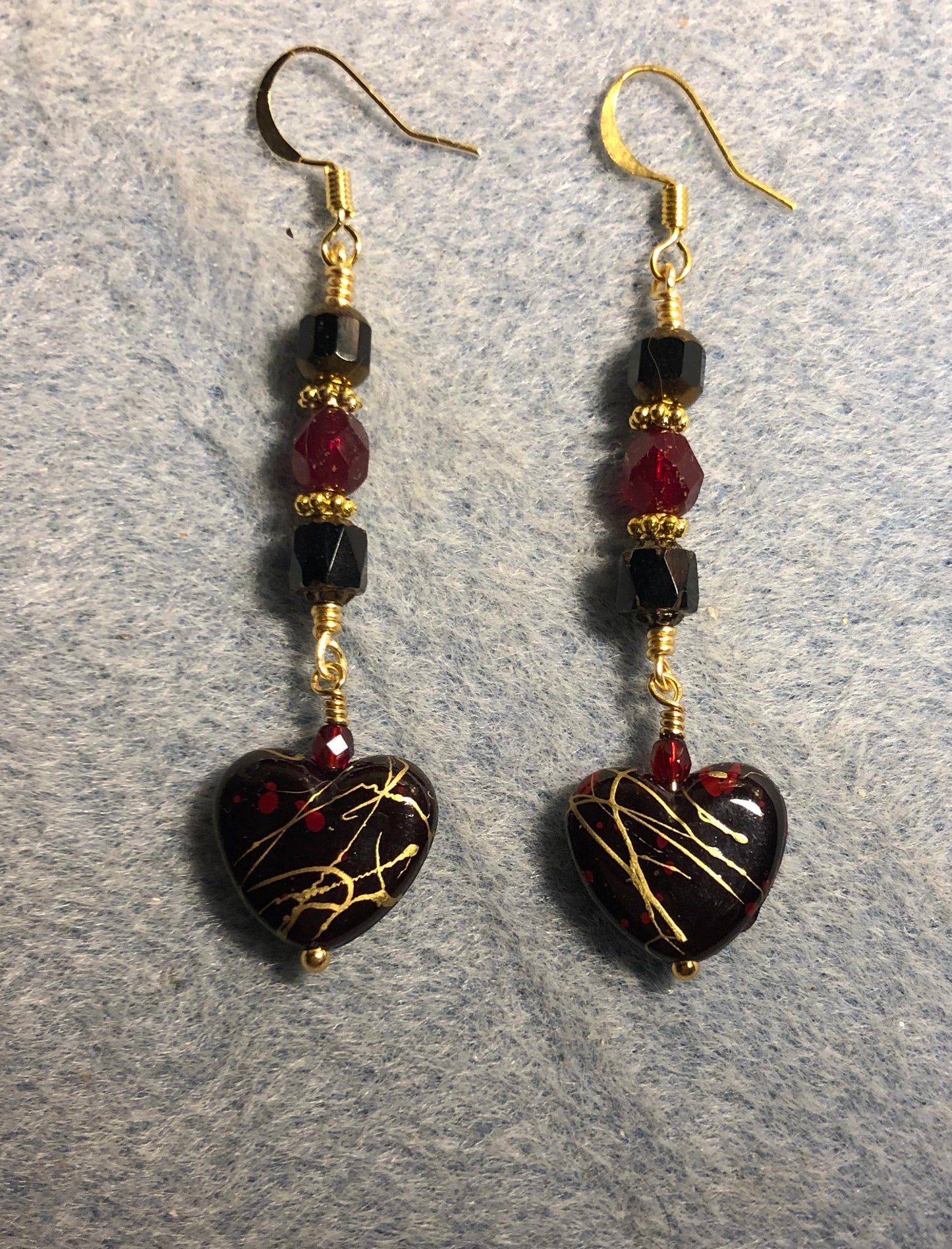 Black, ruby red, and gold acrylic heart bead earrings adorned with black and ruby red Czech glass beads.